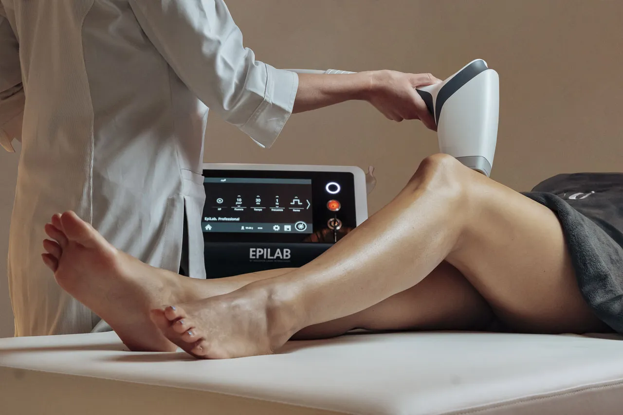 Pièce à main du laser positionnée sur la jambe, paramètres de la séance affichés sur l’écran de l’appareil